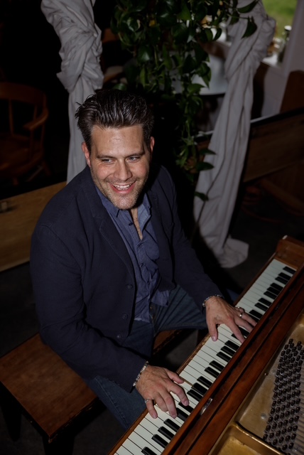 Curtis McLeod seated at the piano in a black and white portrait